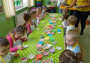 Dzieci dekorują ciasteczka w kształcie pisanki