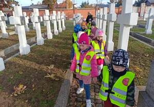 Dzieci w dużym skupieniu i ciszy odwiedzają groby żołnierzy