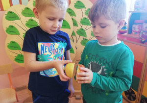 Dwóch chłopców próbuje złączyć połówki jabłka
