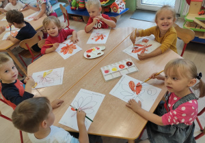 Dzieci malują farbami jesienne liście.