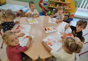 Dzieci malują farbami jesienne liście.