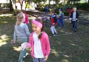 Dzieci zbierają śmieci w ogrodzie.