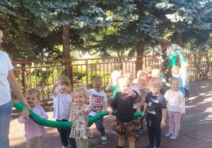 Dzieci stoją przy pluszowy wężu w parach.