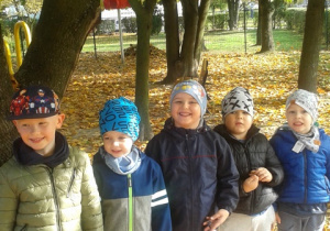 Pięciu uśmiechniętych chłopców stoi przy drzewie.
