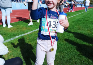 Dziewczynka trzyma pamiątkowy medal.