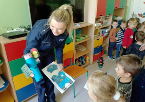 Pani policjantka otrzymuje od dzieci laurki wraz z wykonaną z papieru podobizną policjanta.