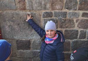 Dzieci oglądają ślad po łapie diabelskiej na ścianie kolegiaty w Tumie