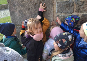 Dzieci oglądają ślad po łapie diabelskiej na ścianie kolegiaty w Tumie