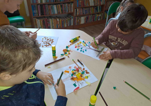 Dzieci wykonują pracę plastyczną - jesienne drzewo techniką wyklejanki
