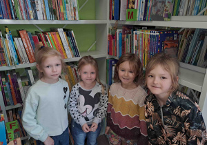 Dzieci na tle półek bibliotecznych z książkami