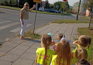 Pani nauczycielka pokazuje dzieciom znak drogowy informujący o przejściu dla pieszych