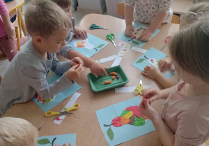 Dzieci samodzielnie wyklejają plasteliną rysunki jesiennych owoców.