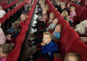 Dzieci siedzą w sali kinowej i cierpliwie czekają na film animowany.