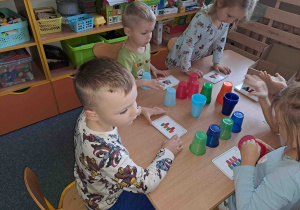 Dzieci tworzą konstrukcje z kubeczków według instrukcji