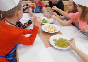 Dzieci wykonują szaszłyki owocowe