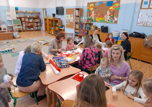 Rodzice przy stolikach pracują z dziećmi