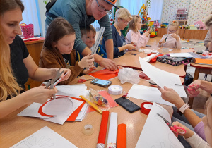 Rodzice przy stolikach pracują z dziećmi