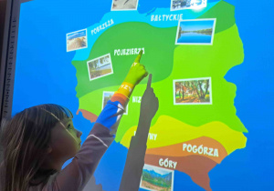 Dzieci wykonują ćwiczenia na tablicy interaktywnej - uzupełniają mapę Polski