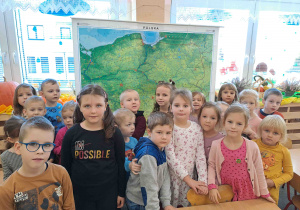 Dzieci stoją na tle mapy Polski