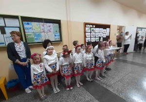 Dzieci stoją w grupie na korytarzu szkolnym w oczekiwaniu na odśpiewanie hymnu