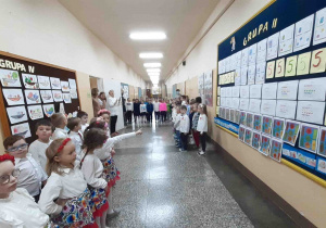 Dzieci stoją w grupie na korytarzu szkolnym w oczekiwaniu na odśpiewanie hymnu