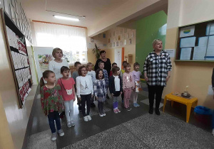 Dzieci i nauczycielki stoją na baczność i śpiewają Hymn Polski