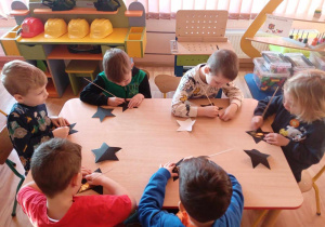 Dzieci za pomocą drewnianej wykałaczki ozdabiają swoją gwiazdkę magicznymi wzorami.