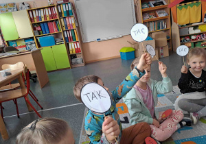 Dzieci odpowiadają na pytania podnosząc kartoniki z napisem "tak" lub "nie"