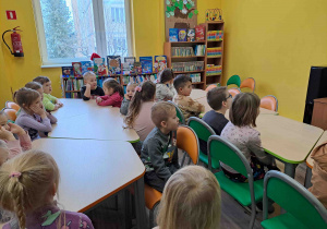 Dzieci w bibliotece słuchają opowieści pani i oglądają prezentację multimedialną dotyczącą Świętego Mikołaja
