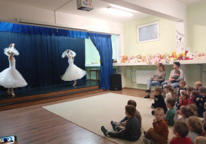 Dzieci oglądają baletnice tańczące na scenie.