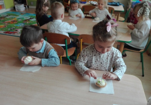 Słodki poczęstunek - dzieci przy stoliku jedzą pyszne babeczki