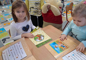 Dzieci oglądają książeczki i prezentują maskotkę misia