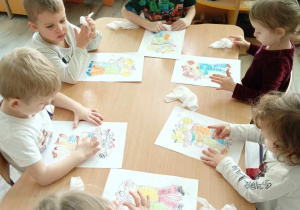 Dzieci rozcierają pastele naniesione na kolorowanki.