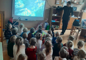 Spotkanie w sali z panem górnikiem. Dzieci oglądają film edukacyjny na tablicy multimedialnej./