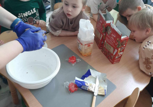 Dzieci przyglądają się jak panie przygotowują składniki w misce na ciasto piernikowe.