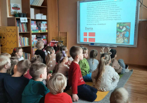 Dzieci oglądają film edukacyjny na tablicy multimedialnej nt Świętego Mikołaja.