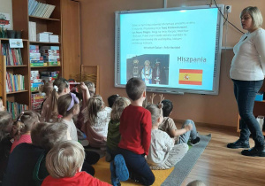 Dzieci oglądają film edukacyjny na tablicy multimedialnej nt Świętego Mikołaja. Pani opowiada dzieciom jak w innym państwie spędzane są Święta Bożego Narodzenia.
