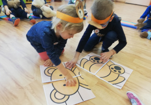 Dziewczynka i chłopiec układają obrazkowe puzzle przedstawiające misia