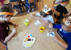 Dzieci malują farbami gipsowe figurki misiów