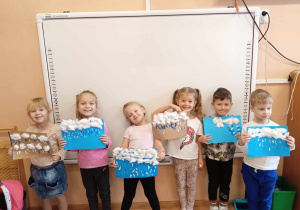 Dzieci z uśmiechem prezentują swoje prace.
