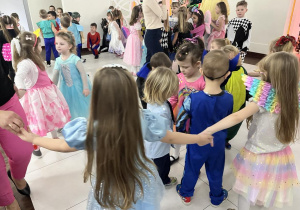 Dziecvi w strojach karnawałowych tańczą w kółeczku