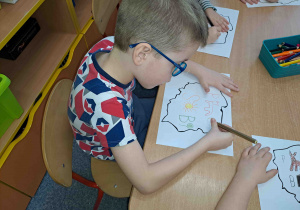 Dzieci uzupełniają kontury Polski literkami i obrazkami