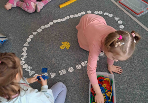 Dzieci na podłodze układają gigantyczne pisanki z klocków