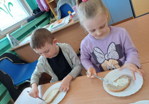 Dzieci smarują chleb twarożkiem
