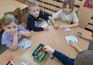 Dzieci umieszczają rysunkowe symbole pogodowe w konturach garnuszków