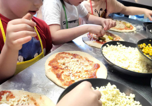 Dzieci wybierają składniki na własną pizzę.