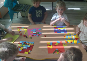 Dzieci układają płaskie figury geometryczne tworząc niepowtarzalne kolorowanki.