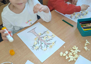 Dzieci wykonują pracę plastyczną z wykorzystaniem popcornu