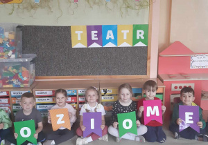 Dzieci pozują do zdjęcia z napisem TEATR POZIOMEK