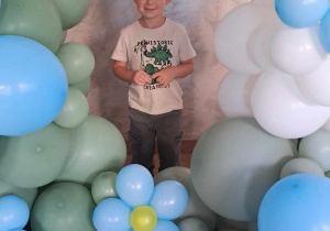 Marcel pozuje wśród dekoracji z balonów
